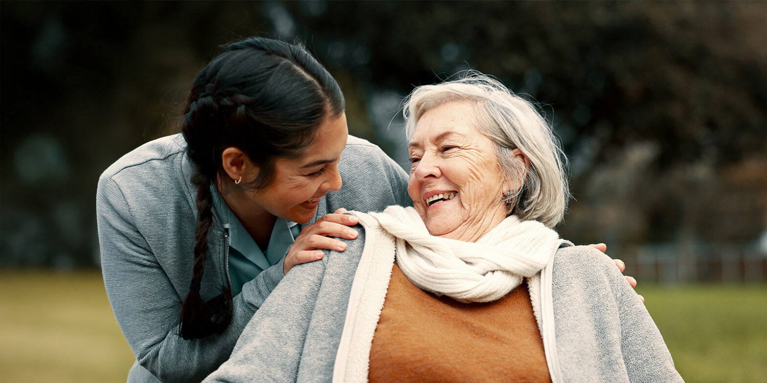 Female caregiver and senior smile at each other