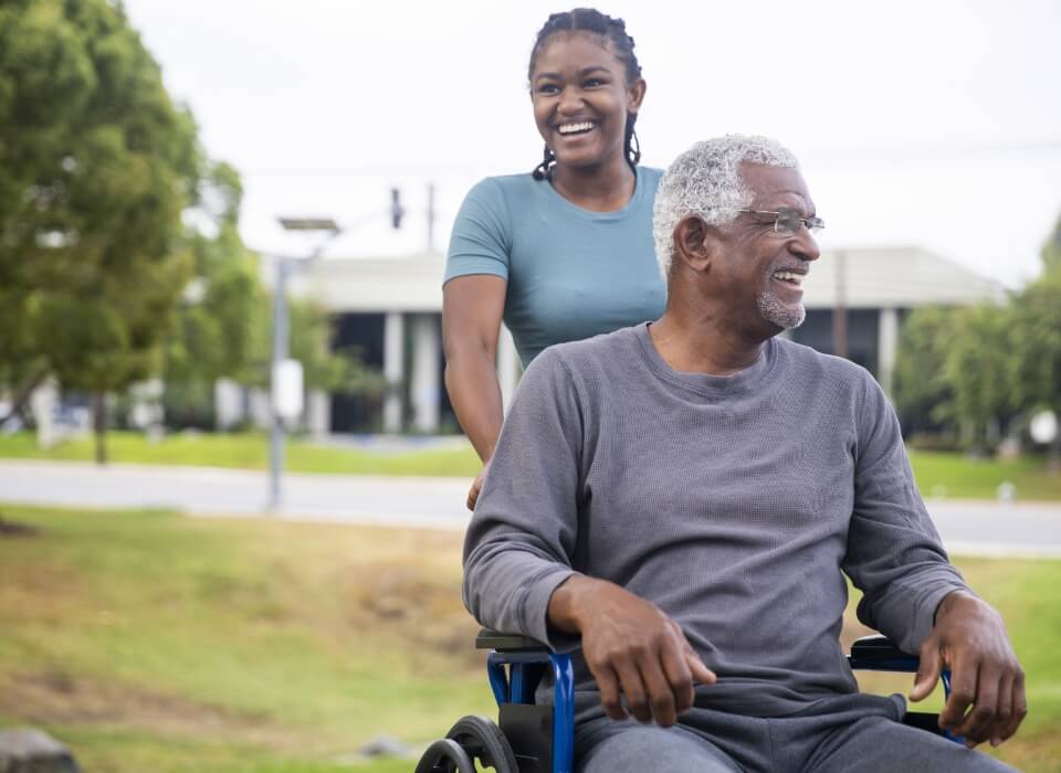 staff member pushing a senior man in his wheelchair