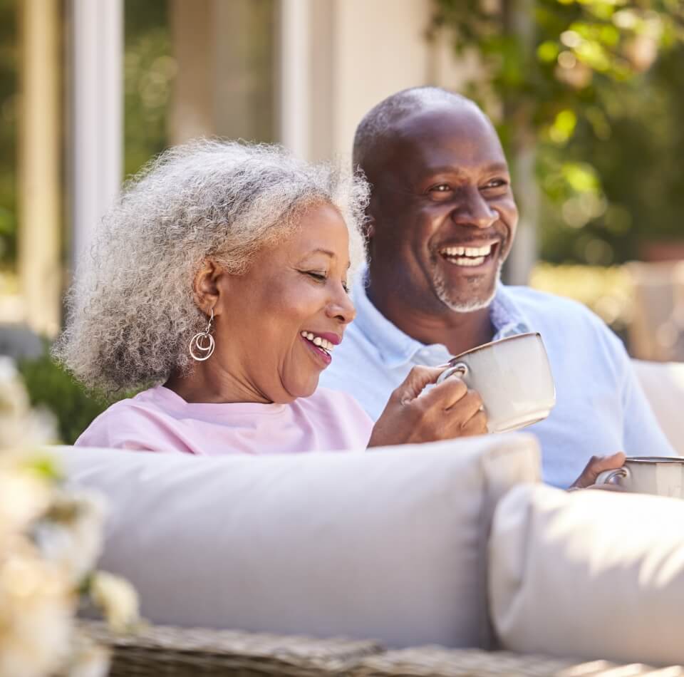 senior couple laughing together while enjoying their morning coffee